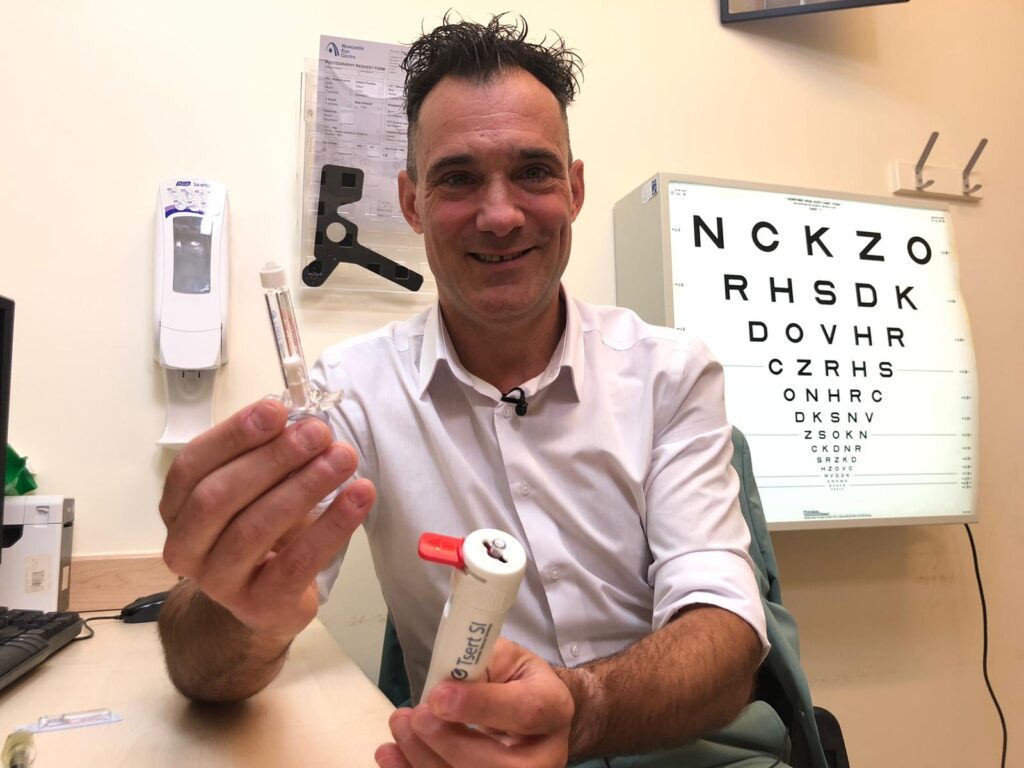Surgeon Sandro holding SING IMTwith eye chart in background
