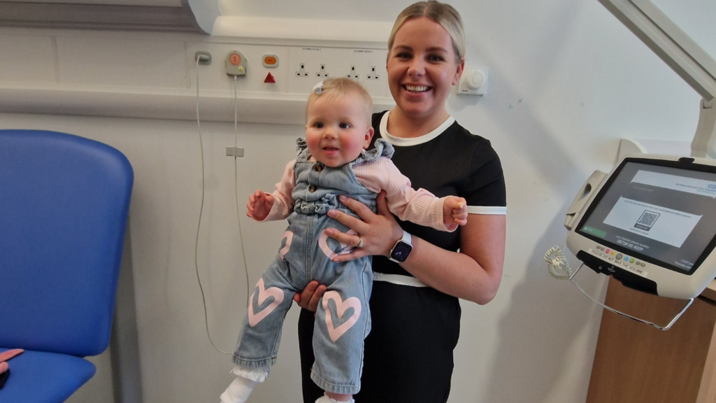 Mum Leona is pictured holding her baby, Hollie-mae, in a hospital room. 