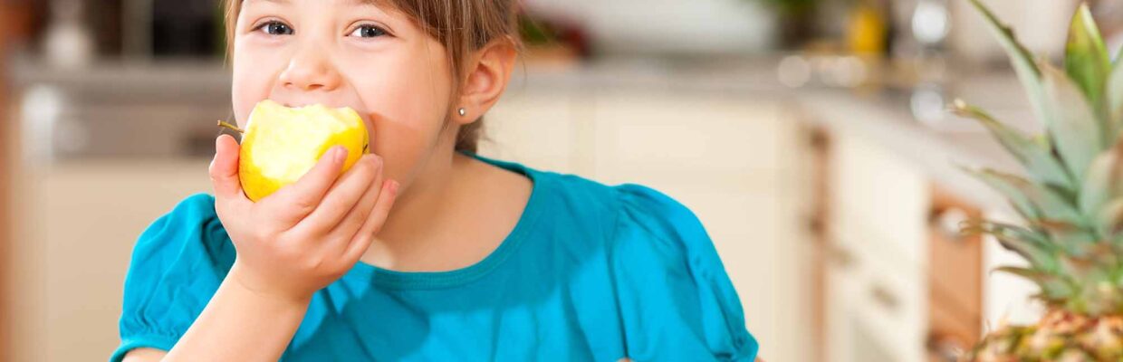 A young girl eating fruit