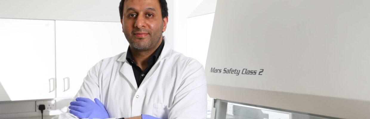 A scientist standing next to a machine in a laboratory