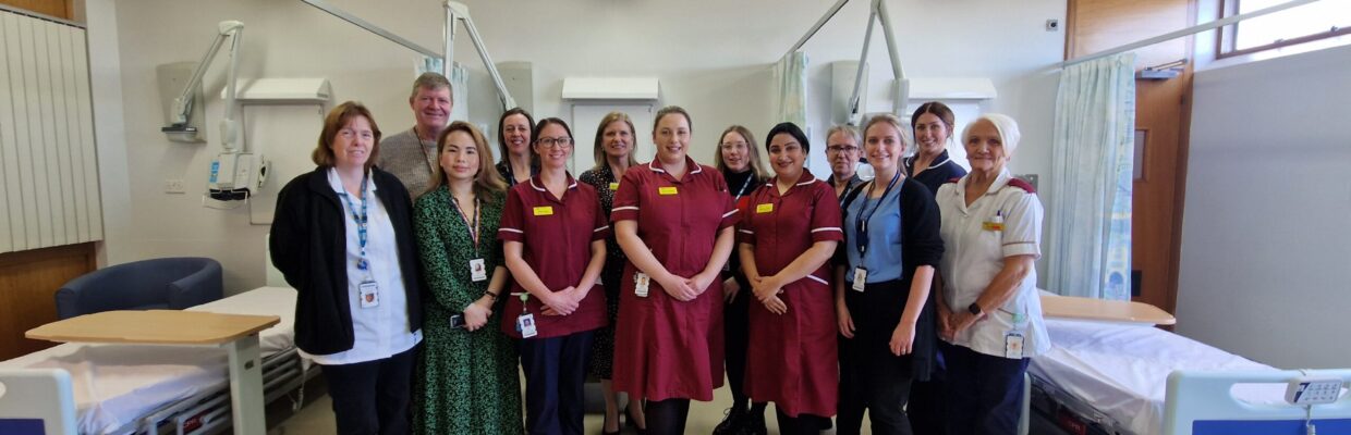 A group photo of medical staff standing between beds on a ward