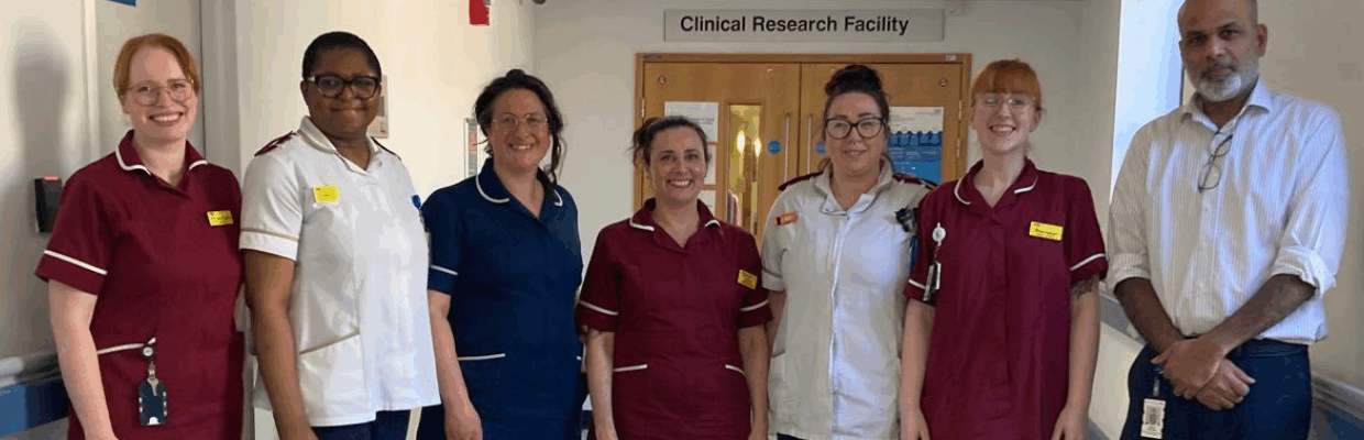 A group photo of medical staff in uniform standing in a hospital corridor by the Clinical Research Facility