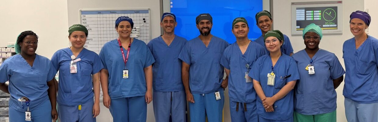 A group of surgeons standing in front of a screen in a theatre